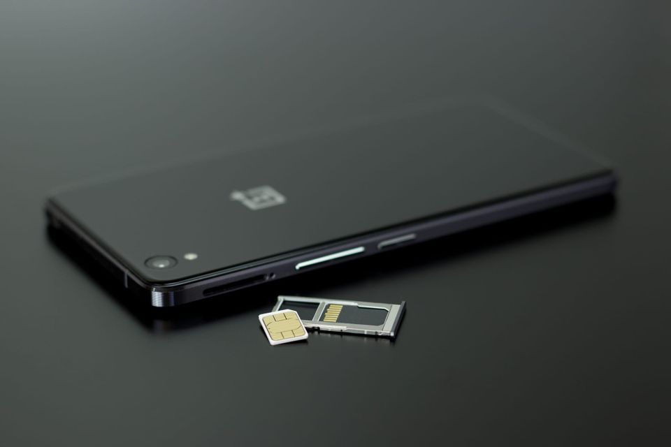 smartphone and SIM card arranged on a dark surface - mobile plan hidden fees