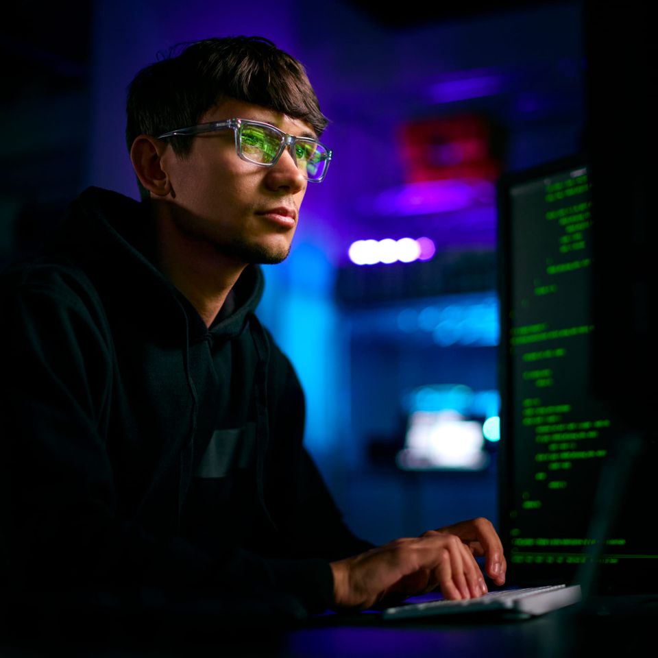 A person types programming code on a screen beside a keyboard and desktop monitor - Gemini 4 Carbon
