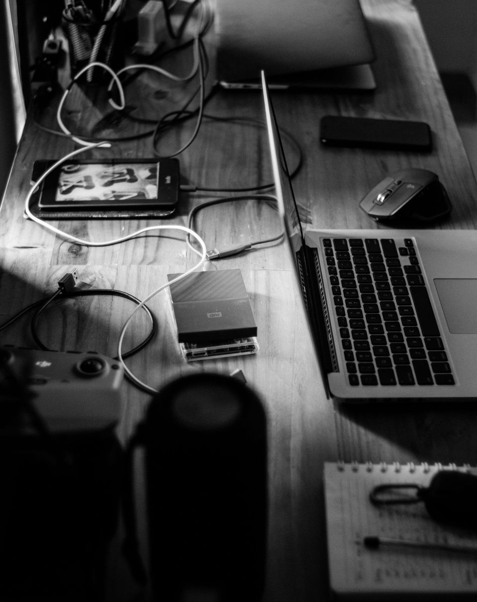 Several external storage drives connected to a laptop on a desk - back up photos