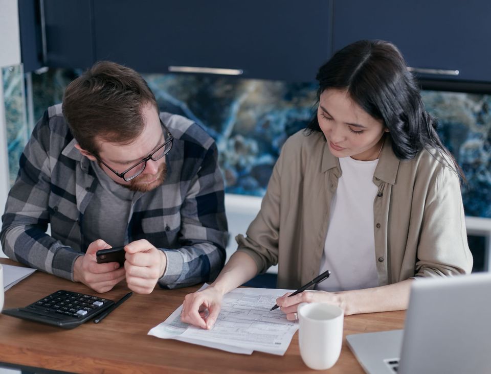 Two adults reviewing paperwork with a calculator and smartphone at a table- 2027 HSA limits