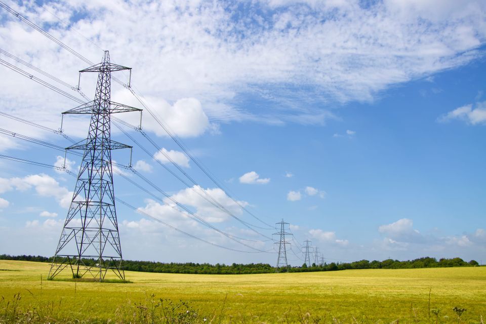 Aerial view of electricity transmission towers and power lines crossing farmland in England.
