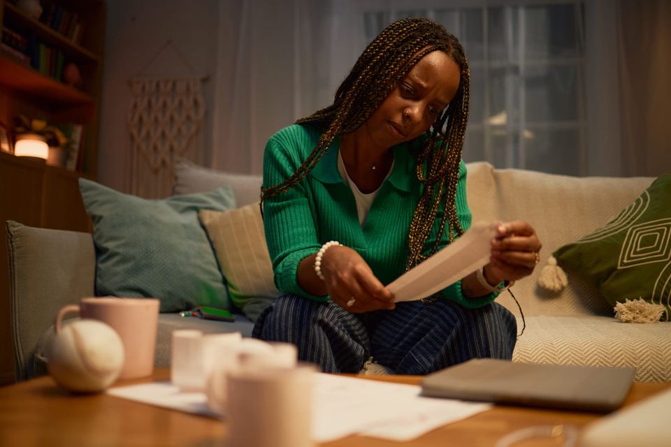 Woman reviewing receipts beside a laptop and notebook at a table - verify health insurance