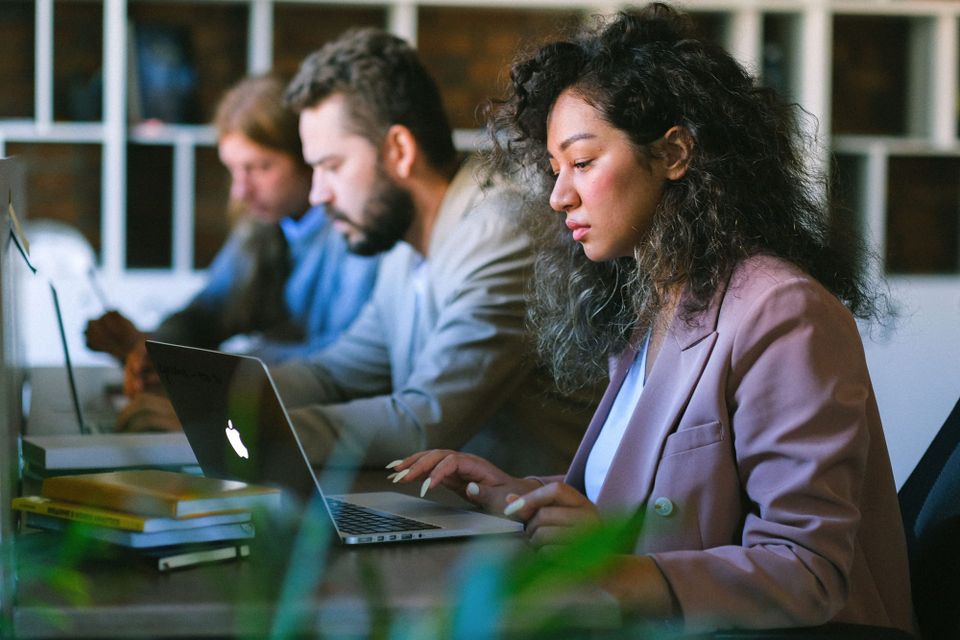 Coworkers working on laptops at a shared office table - Uber ChatGPT Work rollout