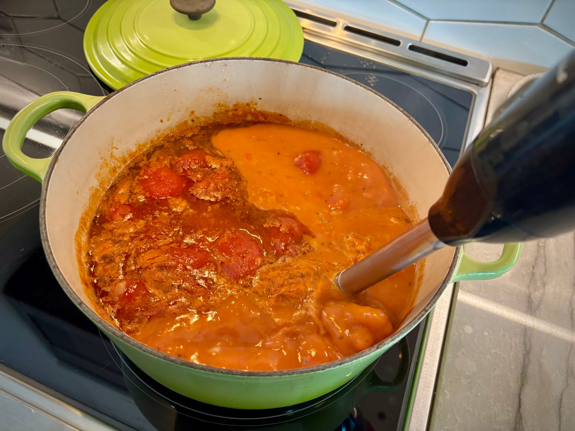 A stick blender, blending a pot of soup