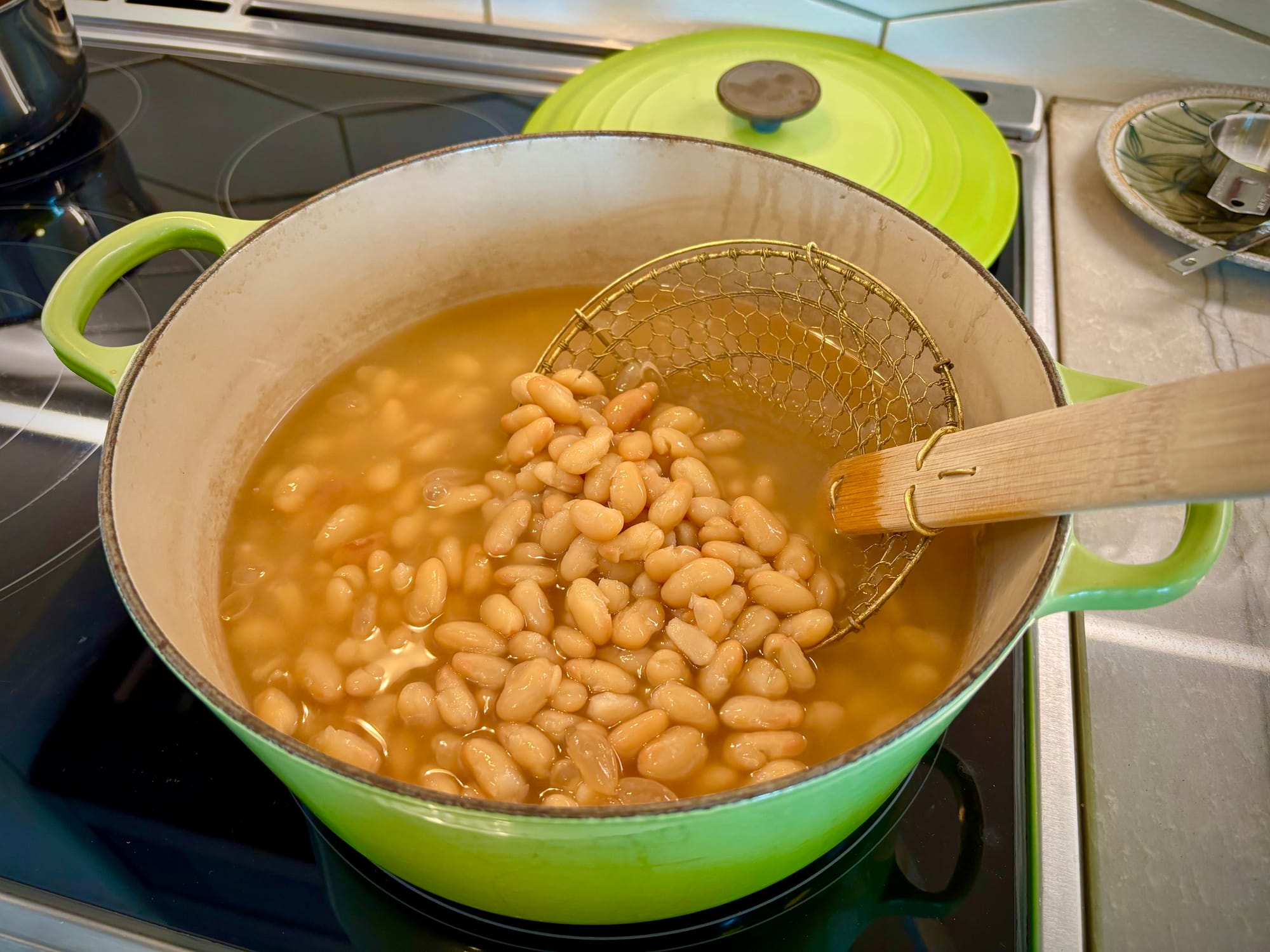 A spider strainer in a pot of beans