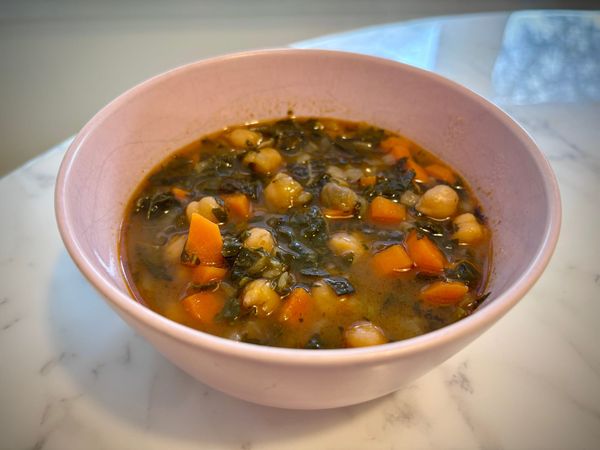 A bowl of chickpea and kale soup with carrots