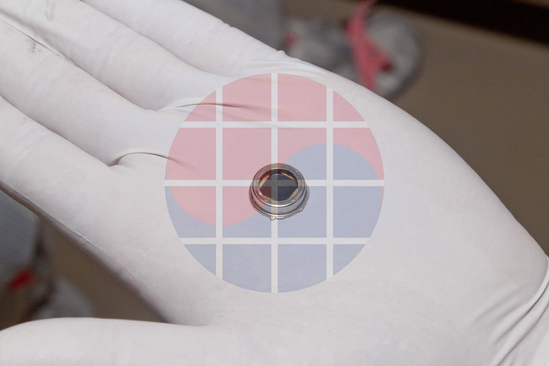 A gloved hand holding a dime-size microchip in a clean room, with a faint VLSI Korea watermark.
