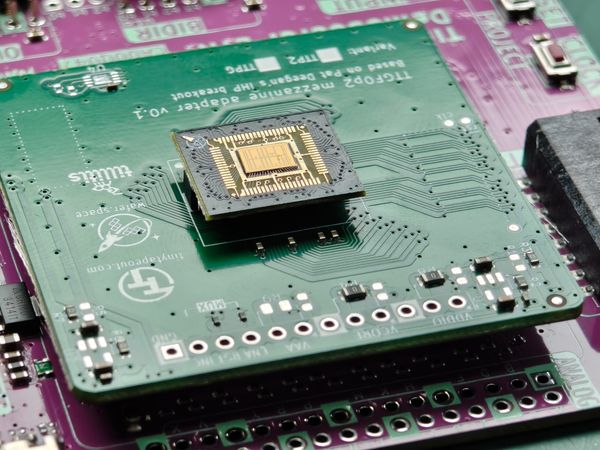 Wafer.space Run 1 chip-on-board part with a visible silicon die and bond wires on a mezzanine adapter board