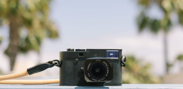 Leica M10M sitting on a railing with palm trees in the background