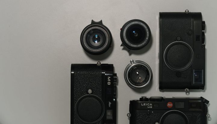 Leica M8, Leica M6, and Leica M10M camera bodies with three lenses on a table