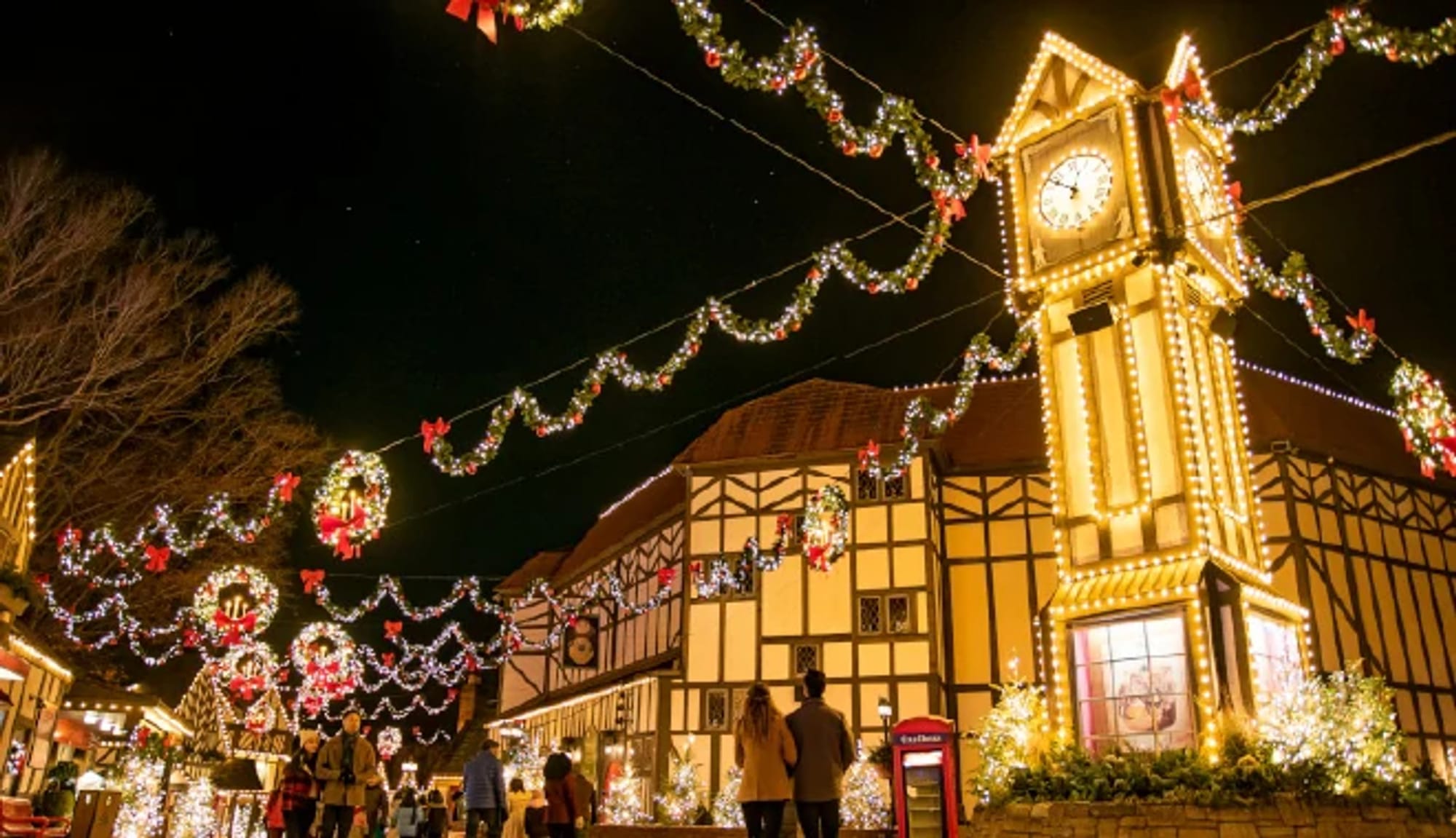 Illuminated garlands and a clock tower along a Tudor-style street at Busch Gardens Williamsburg.