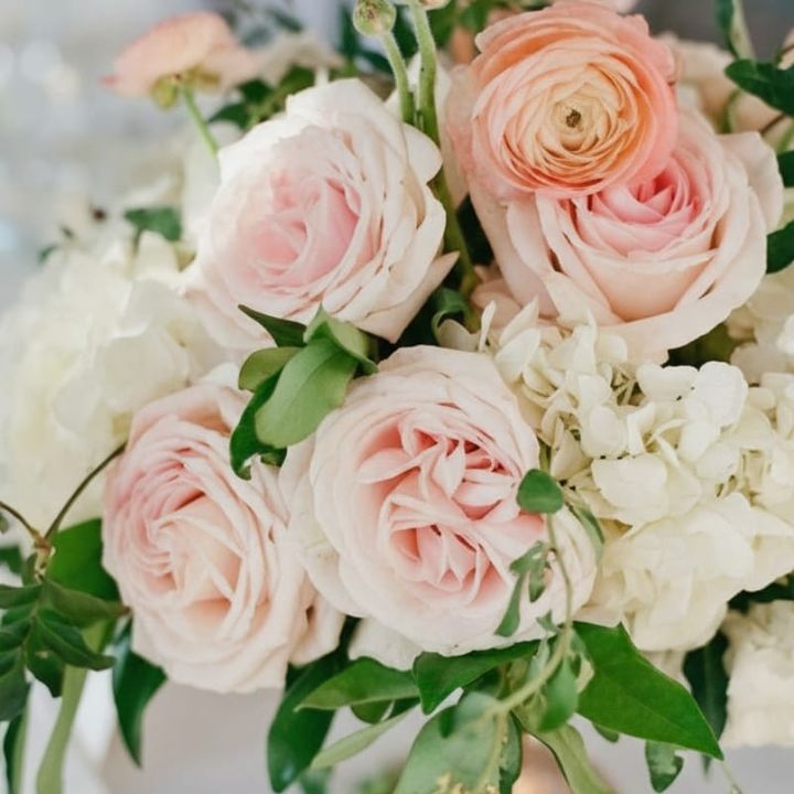 A luxurious wedding reception table at a Naples, Florida venue, featuring a lush floral centerpiece with white and blush roses and elegant place settings.