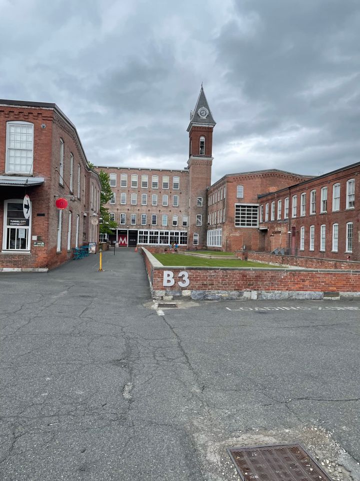 A courtyard entrance to an industrial looking building with a clock tower.