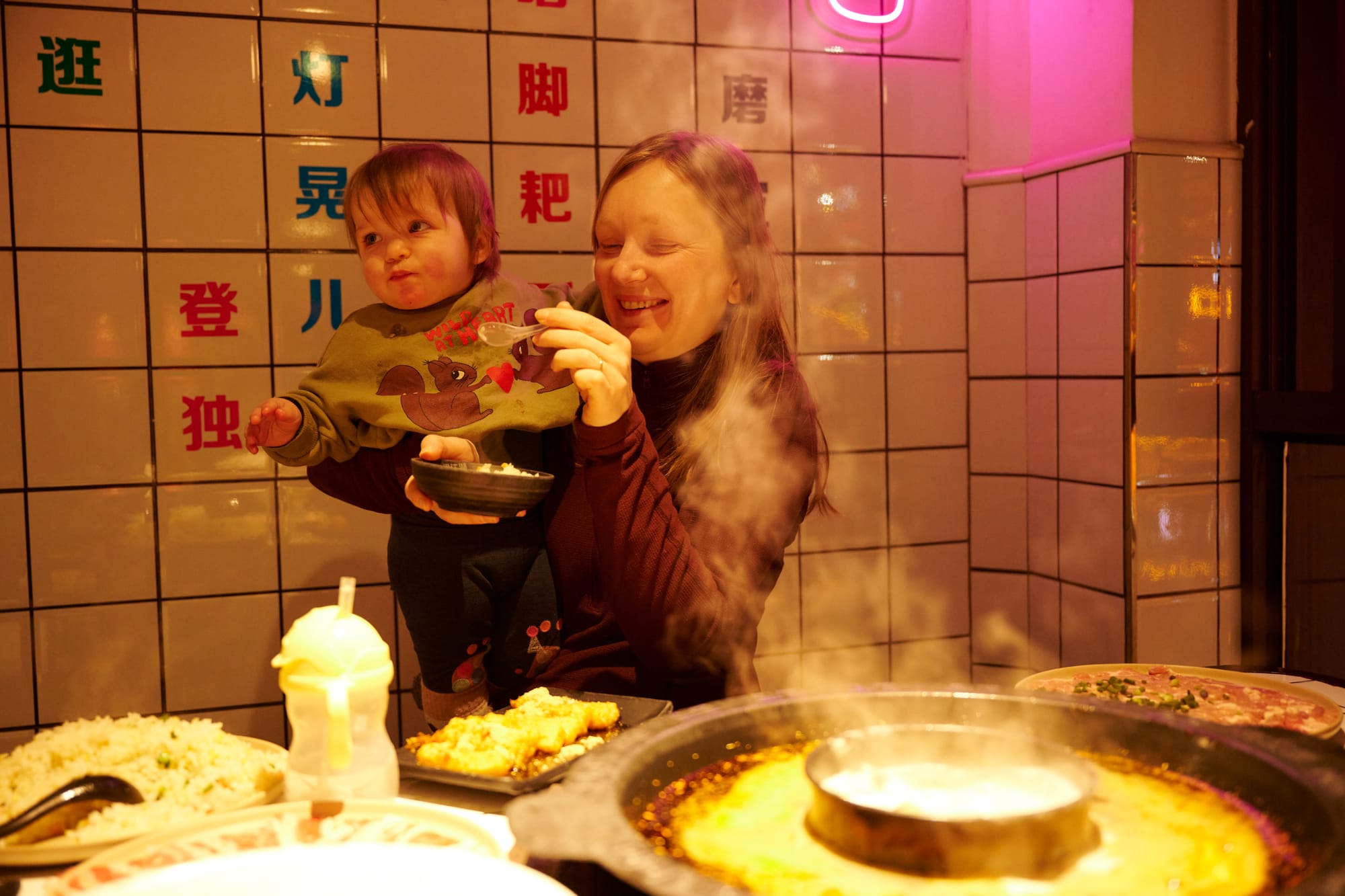 Young child eating rice and hot pot ingredients at a Chongqing restaurant