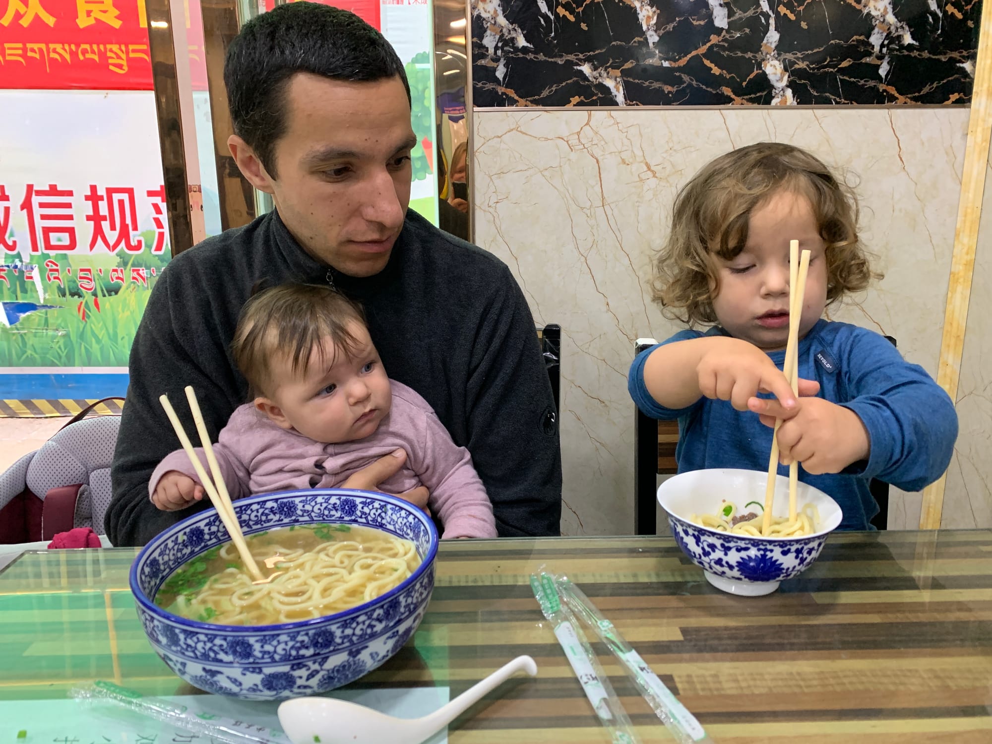 Young child eating Chinese food independently at a table