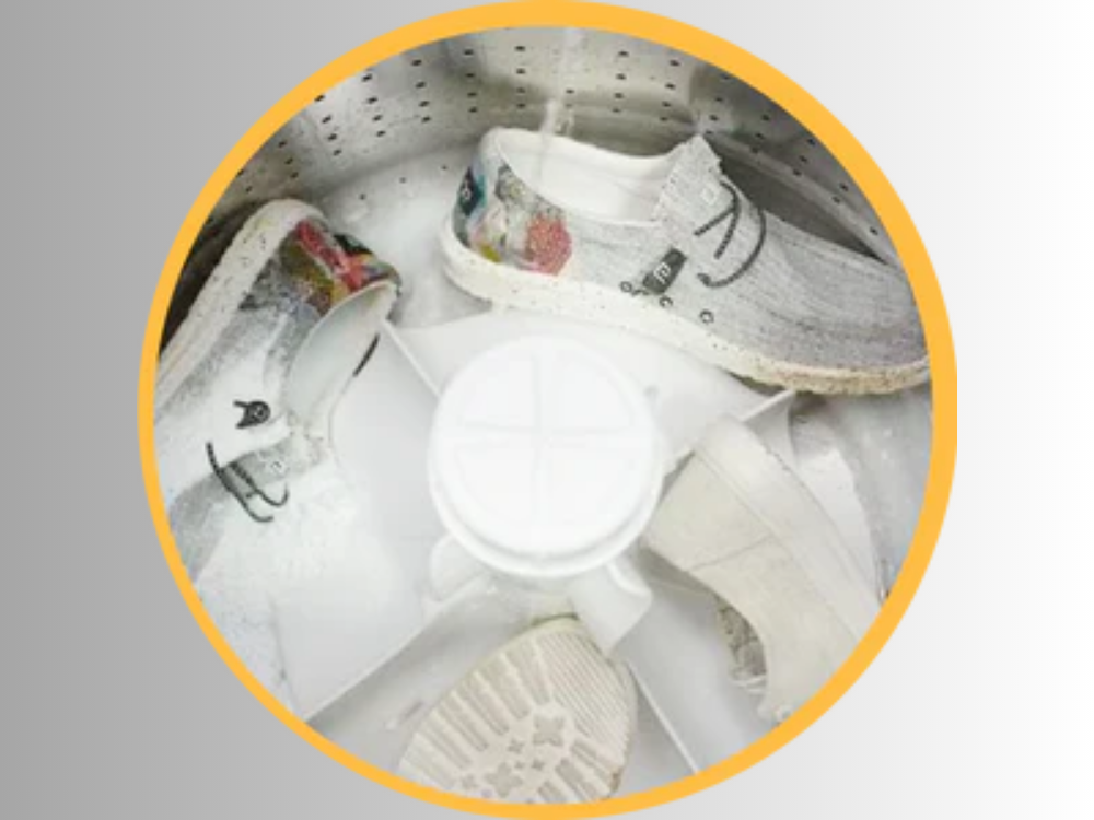 Three pairs of shoes in the washing machine with water spraying in.