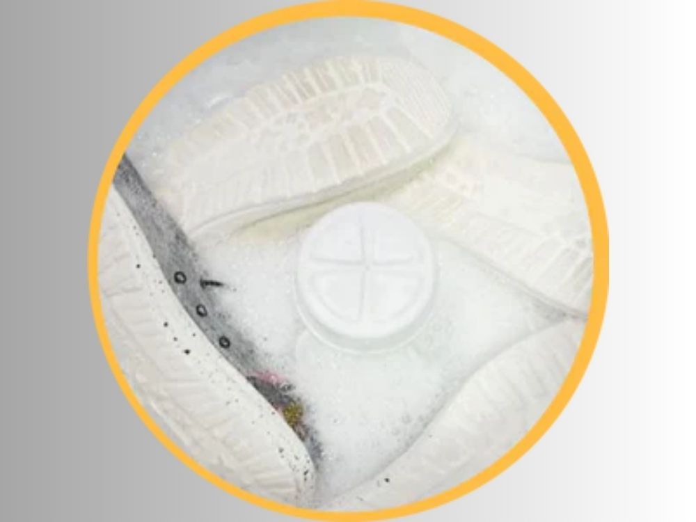 Shoes washing in washing machine, soles up, with many suds.