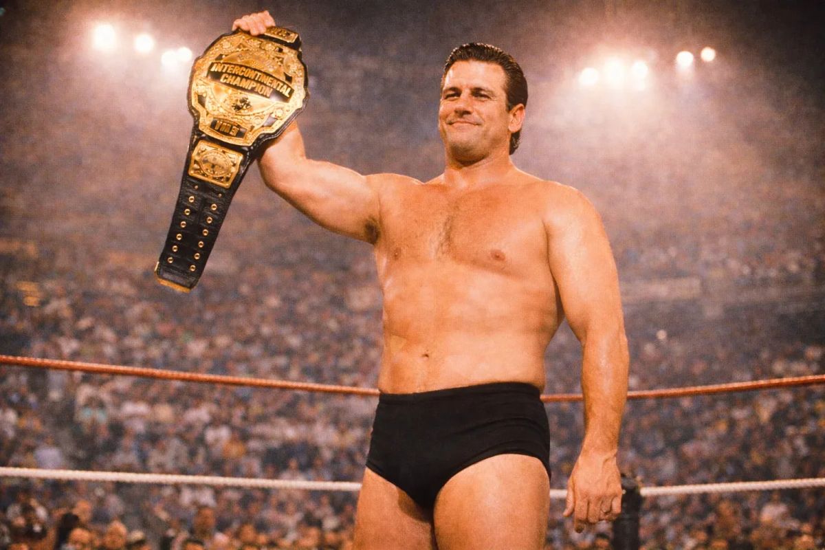 Craig Williams holds the Intercontinental Championship belt aloft in the ring before a crowded stadium.
