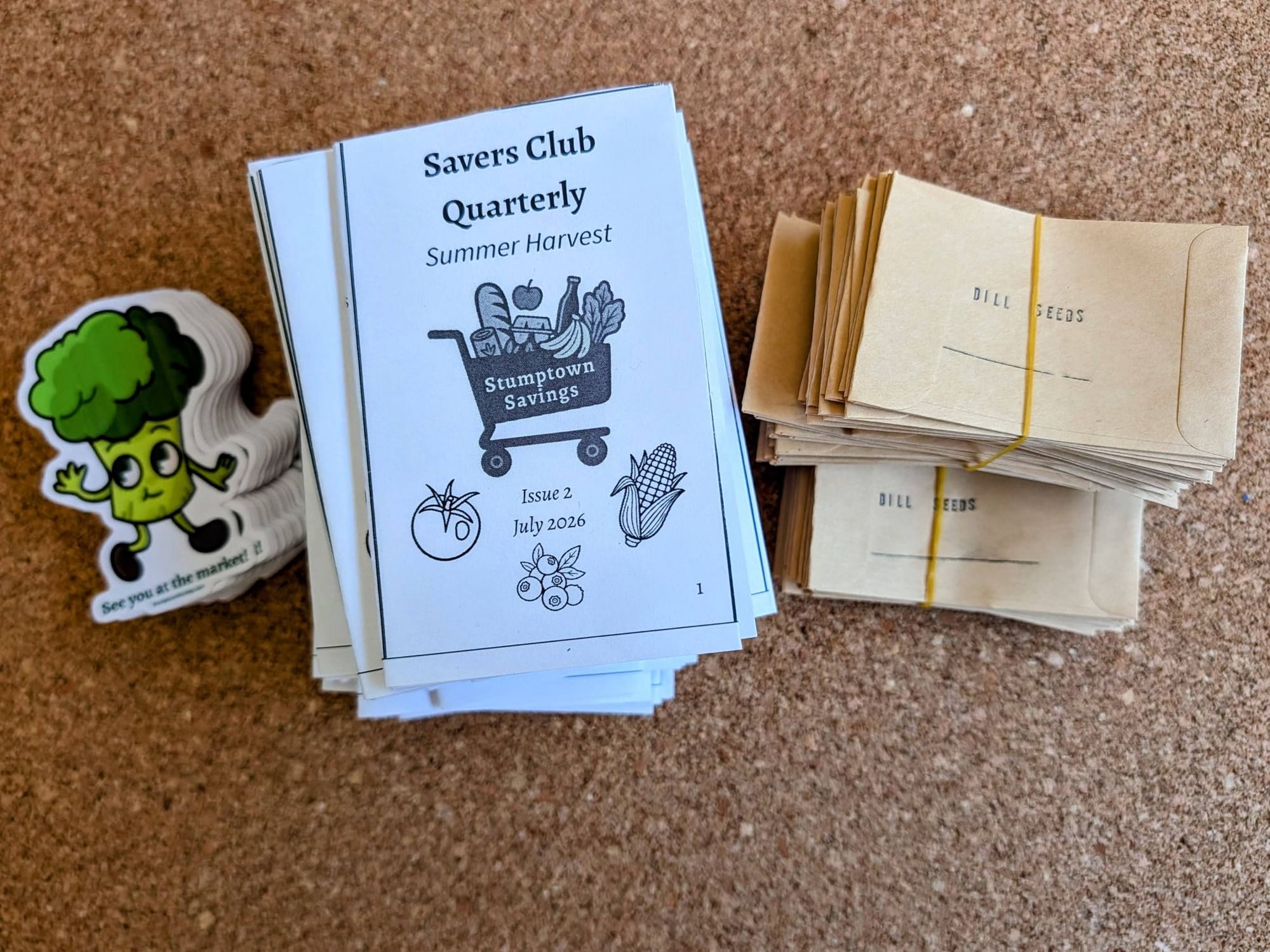 A broccoli headed sticker, a savers club quarterly zine, and packets of dill seeds sent to paid subscribers of Stumptown Savings.