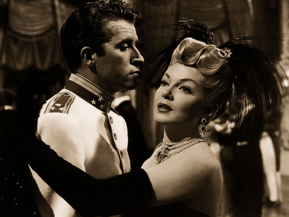 Fernando Lamas con uniforme militar de gala blanco, bailando con una actriz rubia en un salón