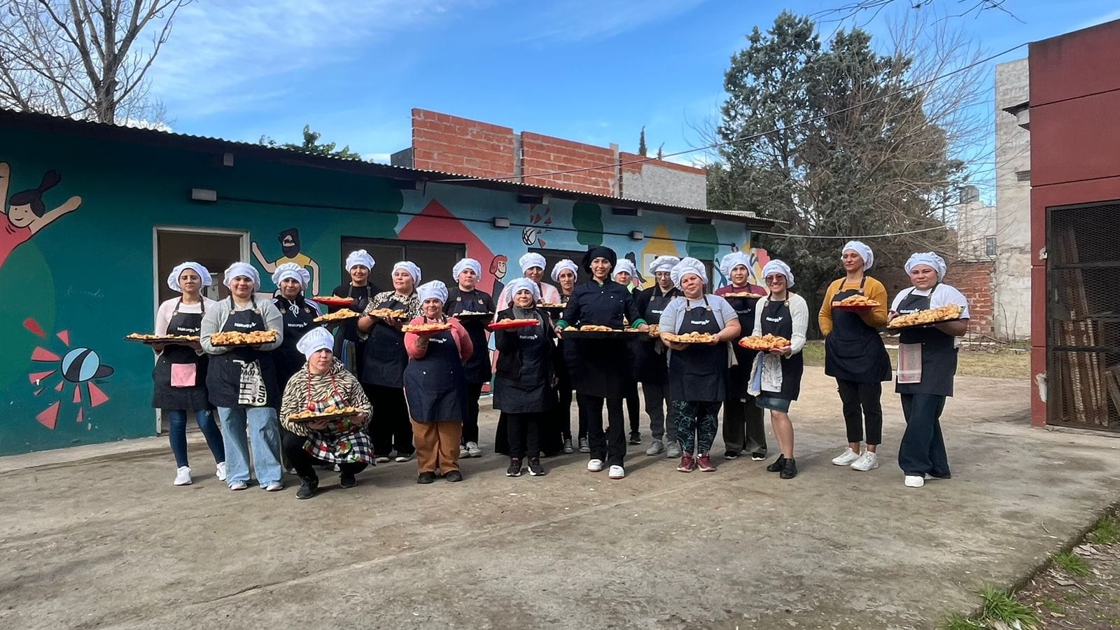El espíritu de la independencia argentina se sintió con un sabor muy especial en el barrio Cascallares de Moreno. En una emotiva jornada que se ha convertido en tradición, Naturgy Argentina, en alianza con la Asociación Civil Siloé, celebró el 9 de Julio agasajando a los vecinos con delicias caseras . Los protagonistas de esta celebración fueron los mismos participantes de Siloé en el programa "Energía del Sabor" de Naturgy Argentina. Esta acción, que se repite año tras año en una fecha tan significativa es un reflejo del impacto transformador del programa. “Esta iniciativa fue la primera experiencia comunitaria de la cohorte 2025 y se llevó a cabo el mismo 9 de julio con el objetivo de hacer la práctica inicial de producción en serie. Resultó sumamente positivo generar este espacio, que no solo incluye aprendizaje sino un servicio para la comunidad de Cascallares. Fue muy emotivo el contacto con los vecinos, disfrutamos mucho la experiencia”, aseguró Lucía Orcaizaguirre, coordinadora de Siloé del programa Energía del Sabor. "Energía del Sabor" es un programa que crea espacios de aprendizaje y jerarquización de oficios gastronómicos, proporcionando a sus participantes las herramientas necesarias para lograr una inserción laboral genuina y sustentable. El objetivo central es claro: brindar oportunidades concretas de desarrollo e independencia económica a quienes se capacitan. La iniciativa no solo se desarrolla en Buenos Aires, sino que también tiene ediciones activas en la Región NOA, expandiendo su impacto positivo a diversas comunidades del país. En la provincia de Buenos Aires, el programa cuenta con el valioso apoyo y la colaboración de entidades clave como la UTHGRA Morón (Unión de Trabajadores del Turismo, Hoteleros y Gastronómicos de la República Argentina), la Fundación Siloé del partido de Moreno y la Fundación Peregrina del barrio Las Tunas, en el partido de Tigre. La actividad es abierta a la comunidad. Esta jornada en Cascallares es un claro ejemplo de cómo la colaboración entre el sector privado y organizaciones civiles puede generar un impacto social positivo en las comunidades.  Podés conocer más de esta experiencia haciendo click acá.