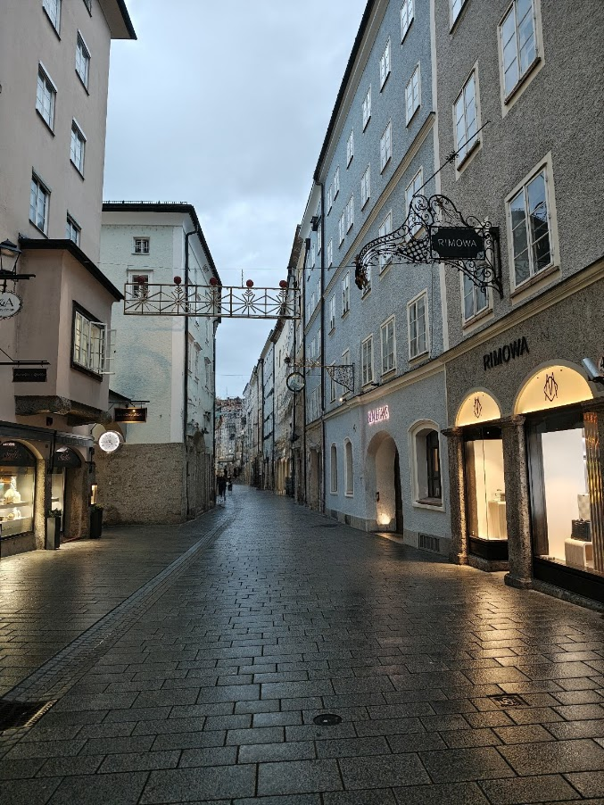 La calle principal y más famosa de Salzburgo: Getreidegasse. Esta histórica vía peatonal destaca por sus angostas edificaciones medievales, sus románticos patios internos y sus característicos letreros de hierro forjado.