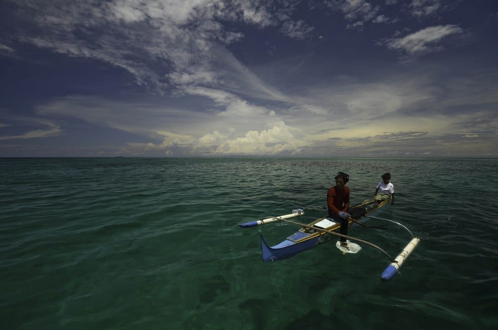 Pescador tradicional Bajau en su canoa de madera preparándose para una inmersión submarina