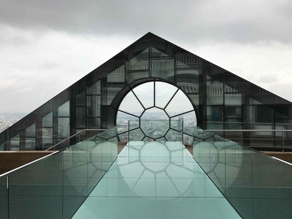 Piscina en altura con frente vidriado de forma triangular y vista panorámica a la ciudad desde lo alto de un rascacielos.