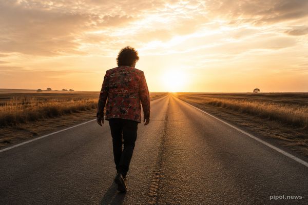 Miguel Abuelo caminando por una ruta hacia el horizonte, al atardecer
