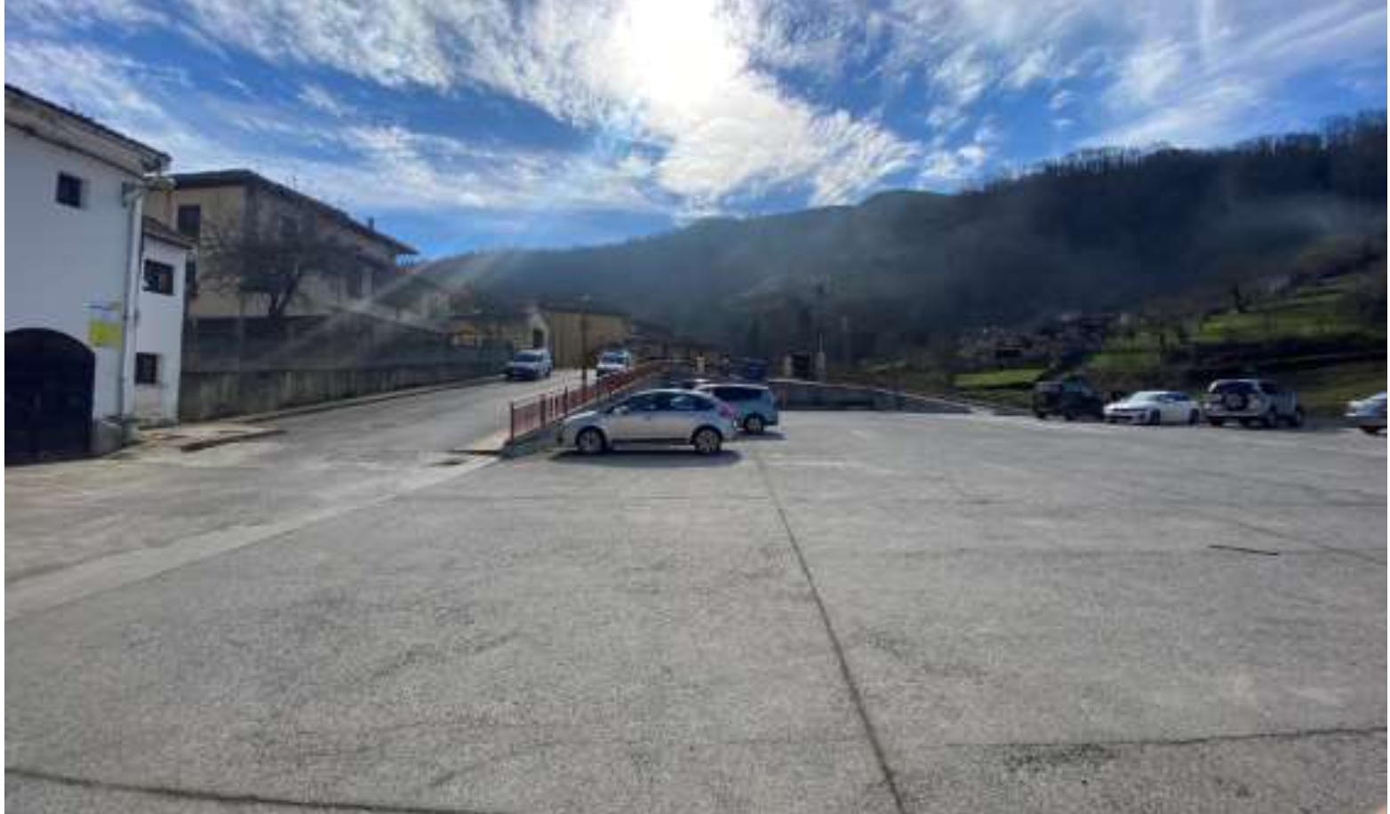 Vista panorámica de la explanada de hormigón bruto desolada, limitada por un muro gris de tres metros de altura que bloquea la transición peatonal hacia la calle de acceso superior