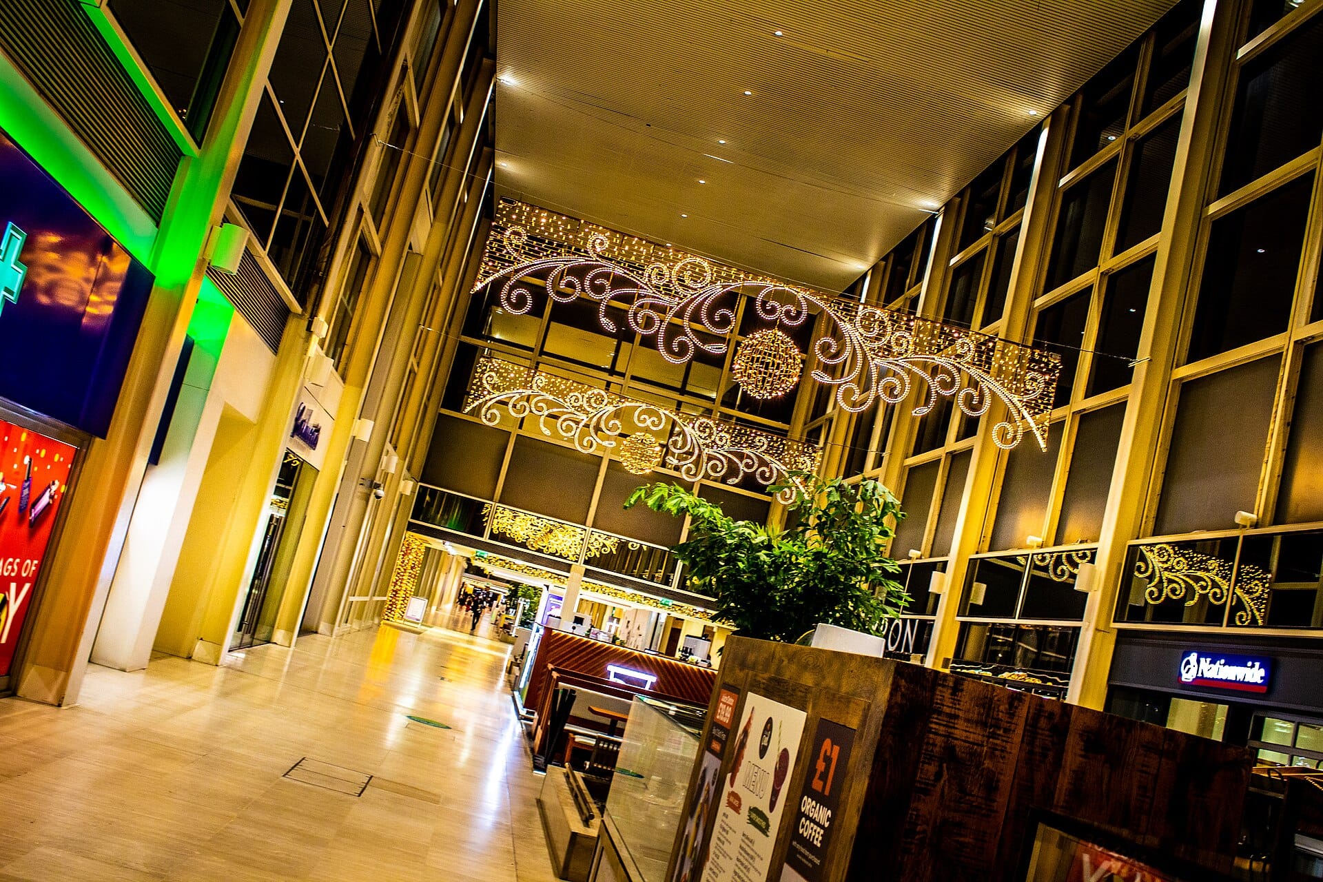 Shopping mall concourse decorated with gold Christmas lights during the holiday season.