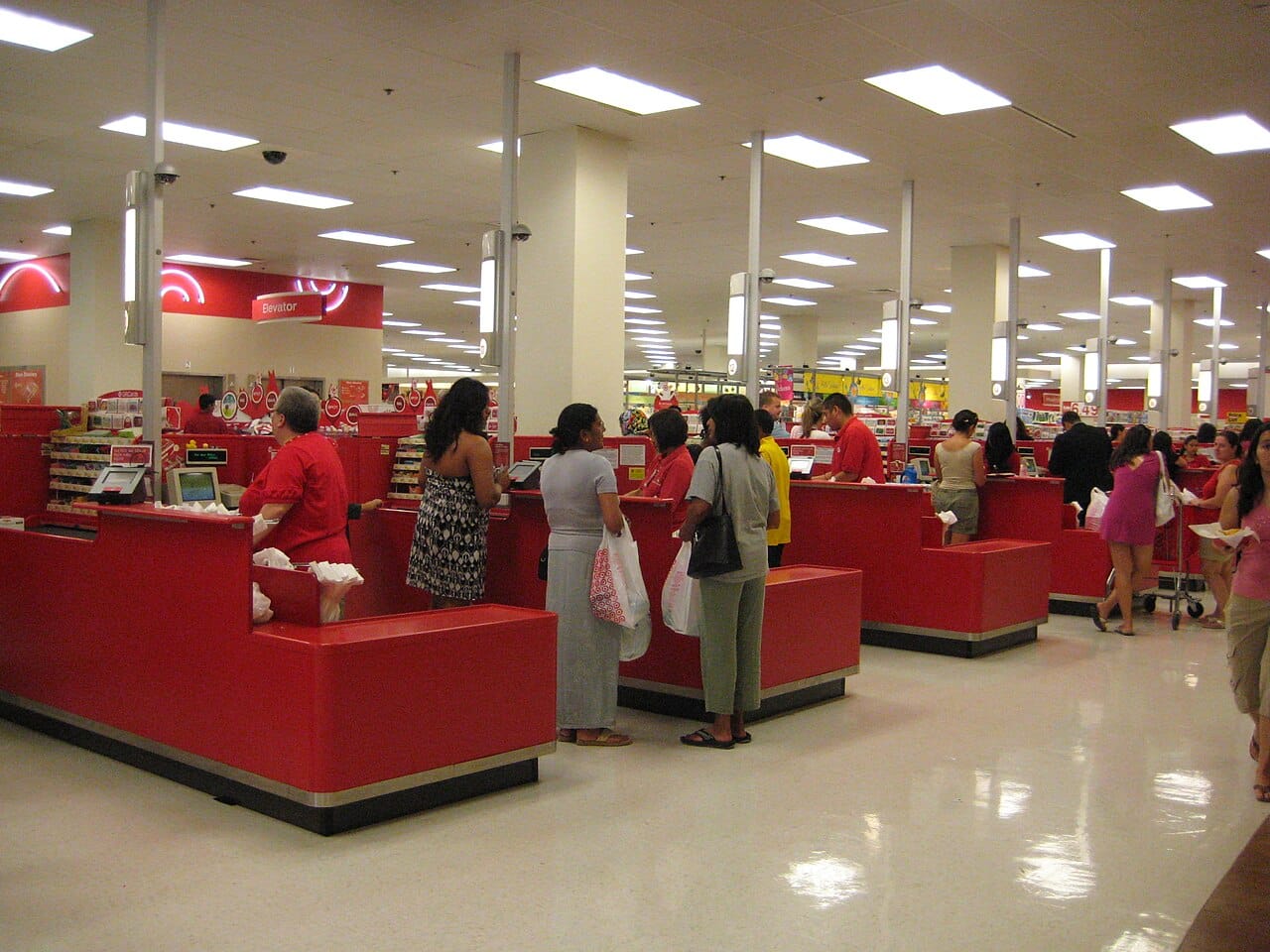 A row of staffed checkout lanes and cash registers in a large retail store
