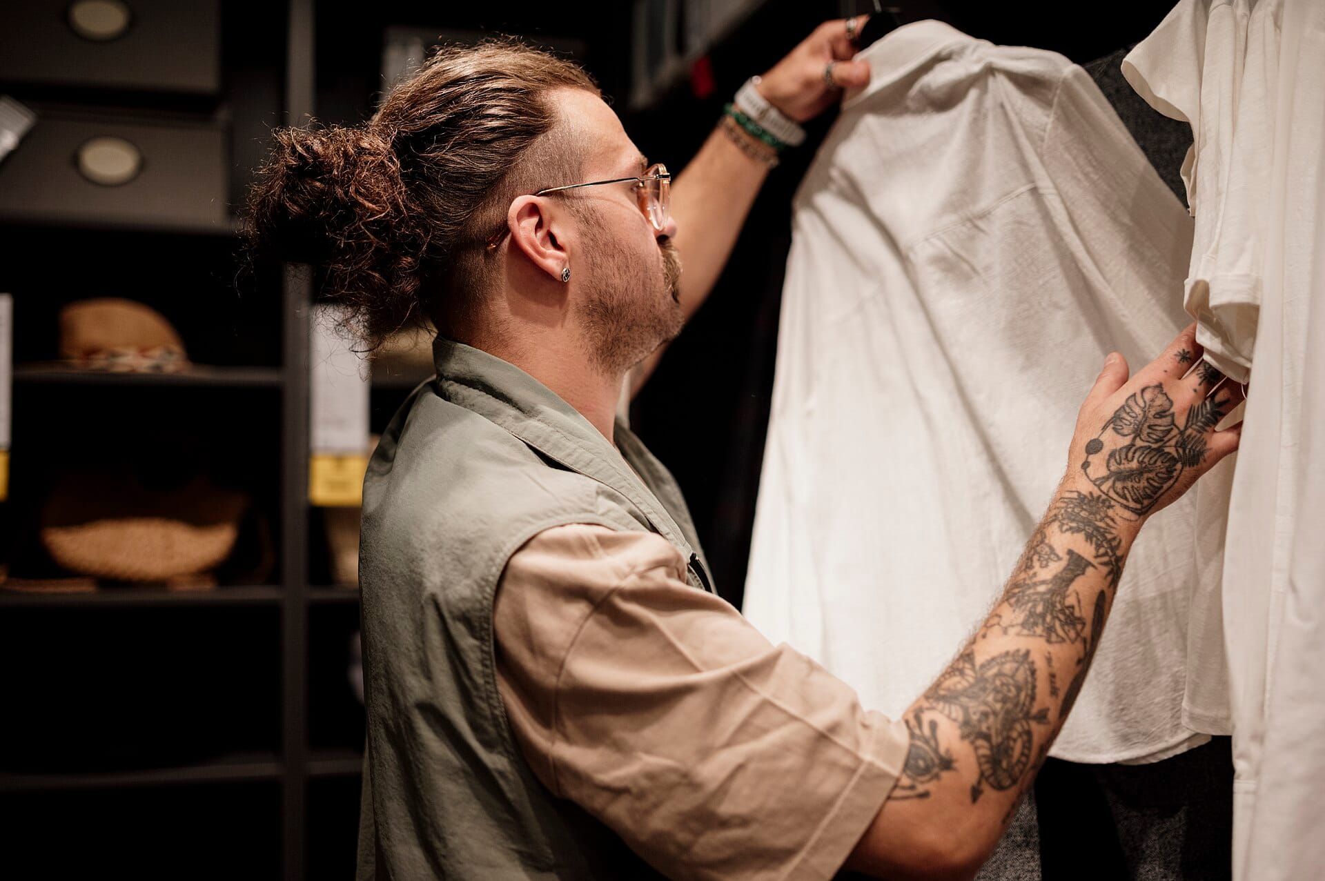 A shopper examining a white shirt on a rack inside a clothing boutique