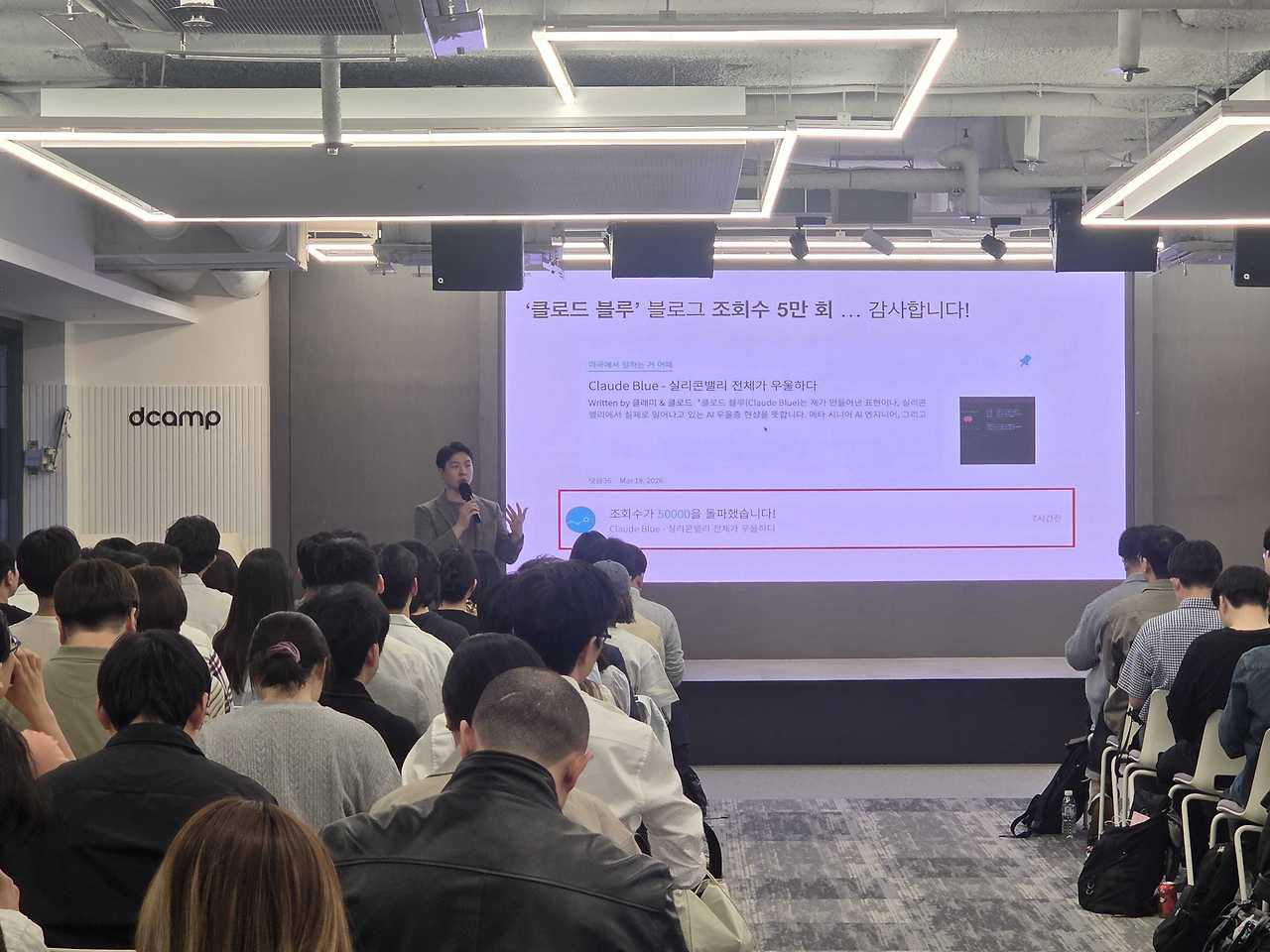 디캠프 강연장을 가득 메운 참석자들과 앞쪽 스크린 앞에 선 발표자