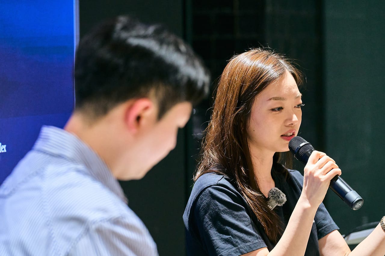 Yuna Kwon answering into a mic, the host listening beside her