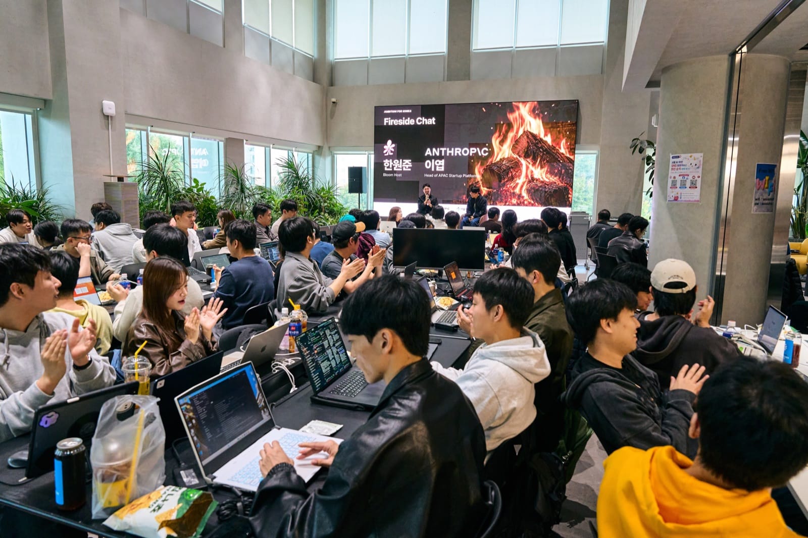 A packed room of participants clapping during the fireside chat, the Anthropic and Bloom names on the LED behind