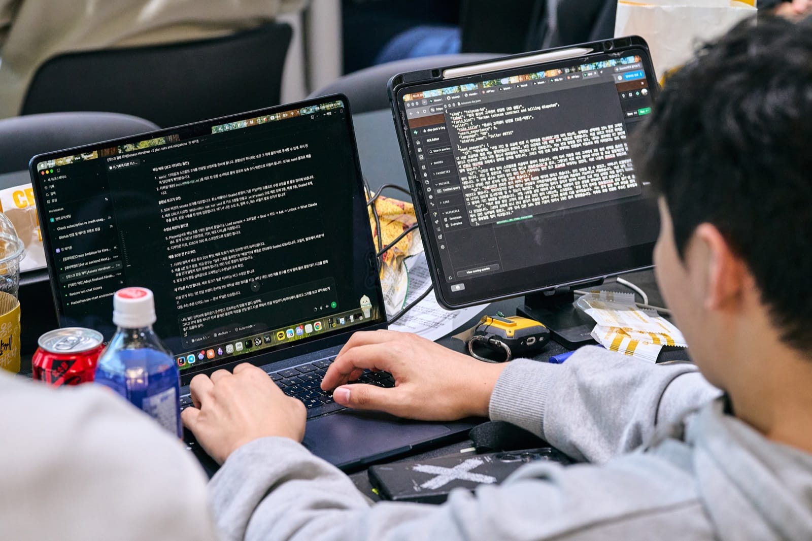 A participant's hands on the keyboard, code open on a laptop and on a tablet propped up beside it