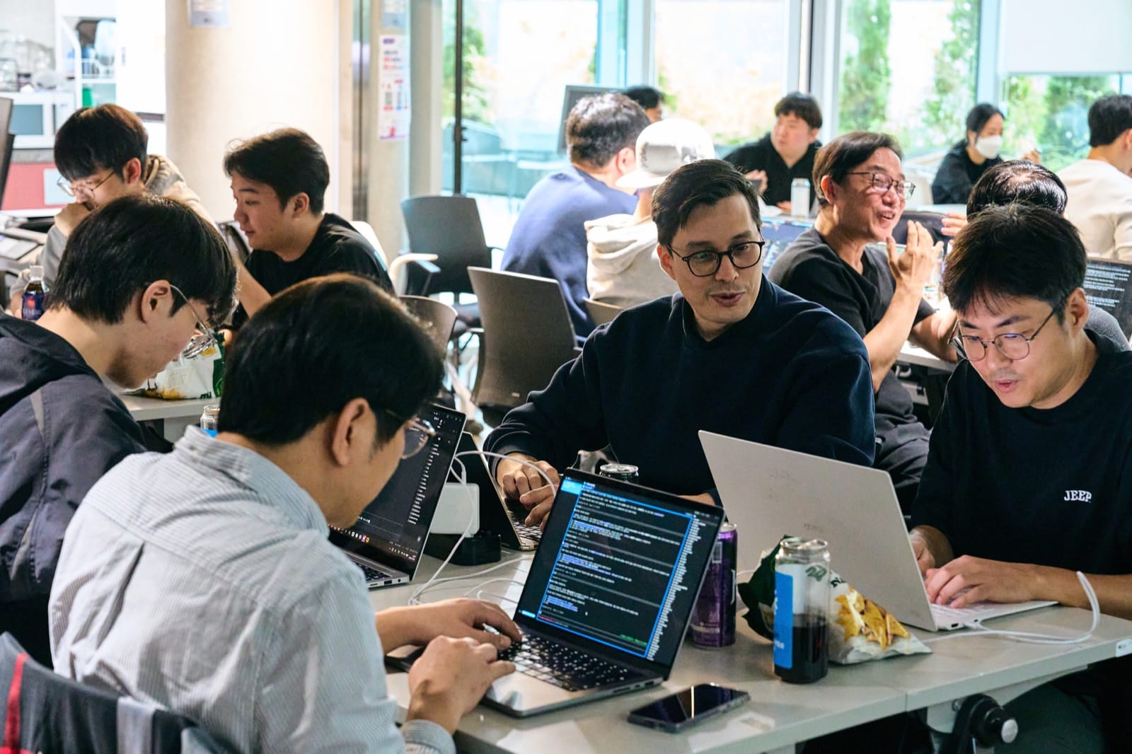 Participants gathered around one table with laptops open, one of them talking through the code with the others