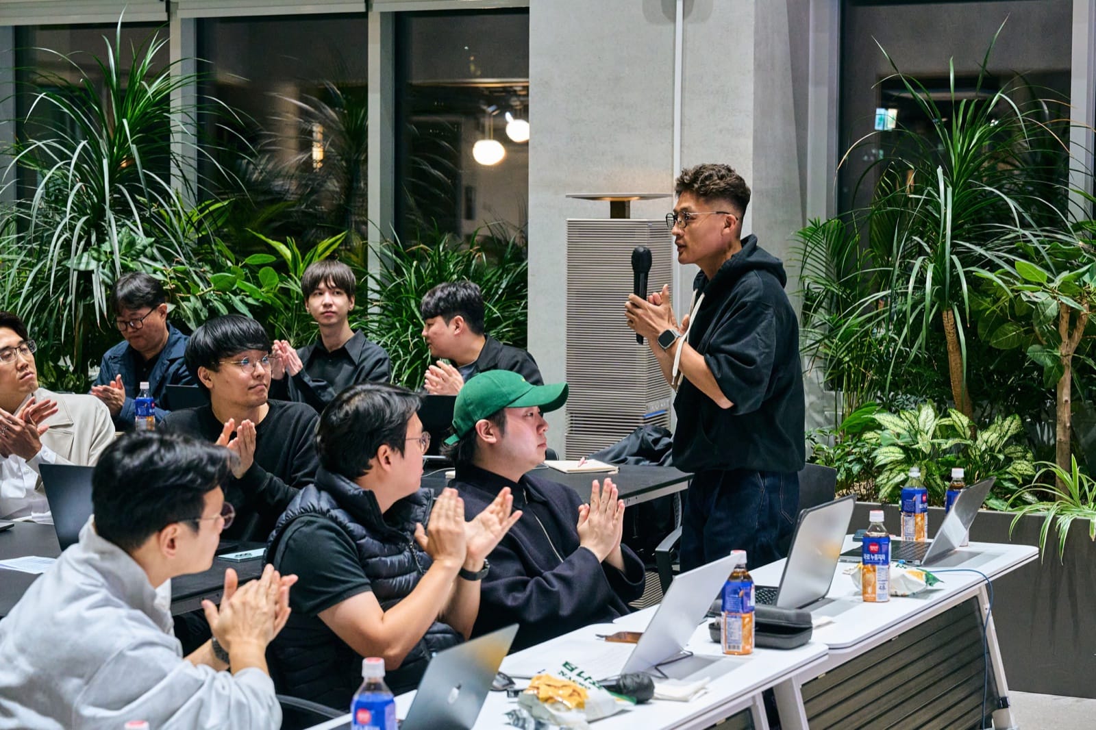 At the Shark Tank, a VC stands with a microphone at the judges’ table while the people around applaud