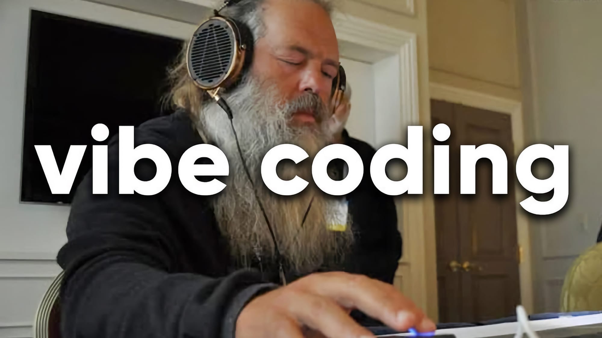 Man with long beard and headphones focused on a music production controller