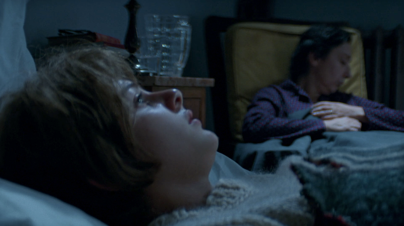 Lenu sleeping in bed in the foreground while Immacolata sleeps in a chair in the background.