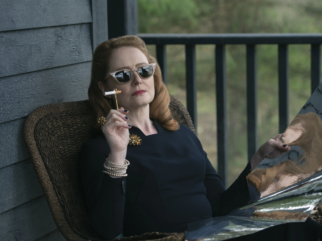 Zelda Spellman, from S1 of "Chilling Adventures of Sabrina," sitting on her porch, wearing a fab pair of sunglasses and smoking a cigarette using a holder ring.