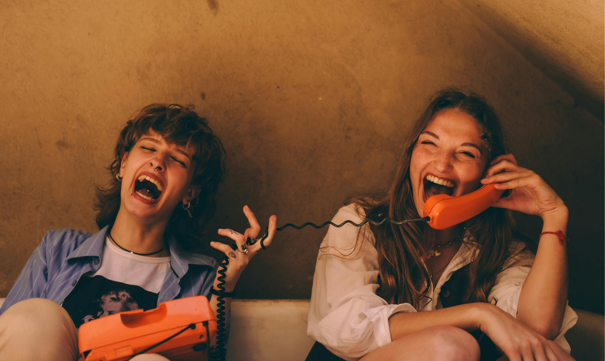 Two girls laughing while one holds a corded phone