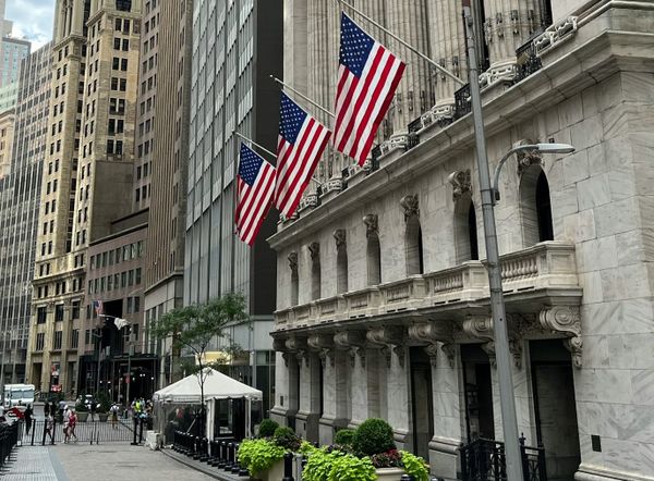 Wall Street financial district with bank buildings and stock market data displayed.