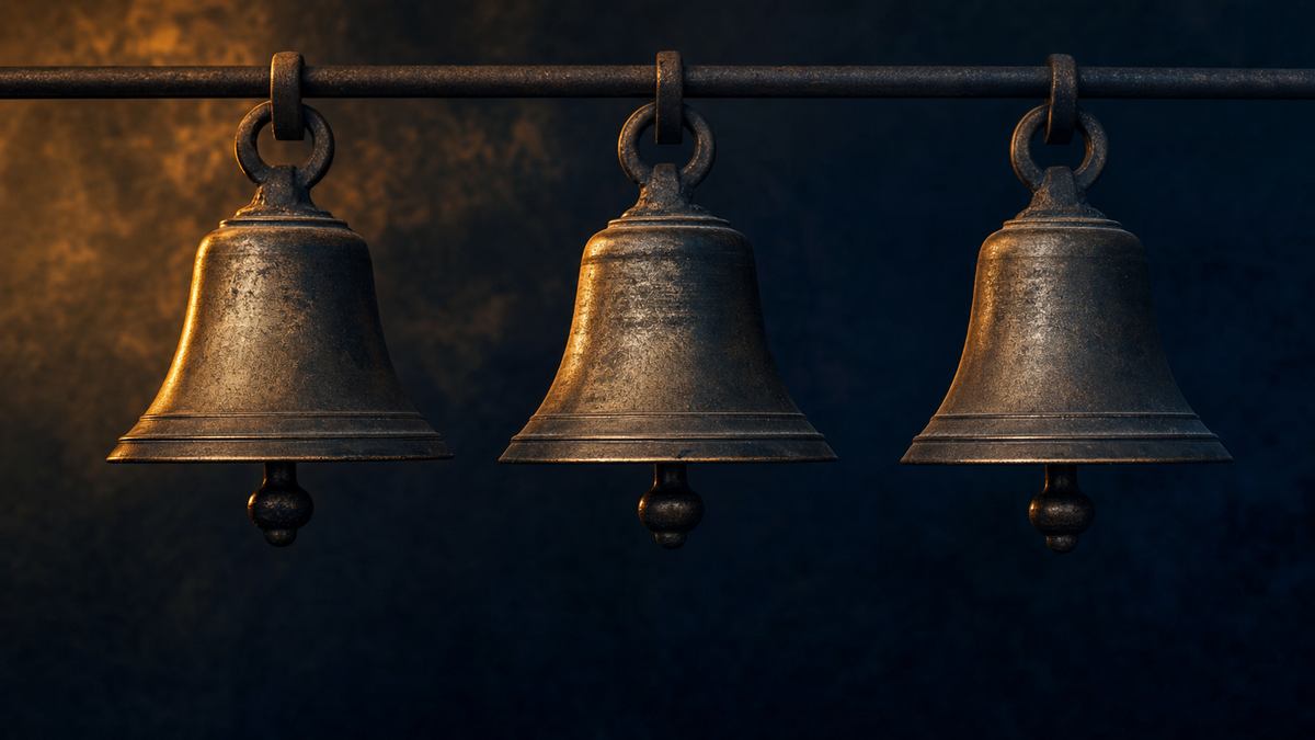Three vintage brass bells suspended in a row against a dark navy background with amber rim lighting