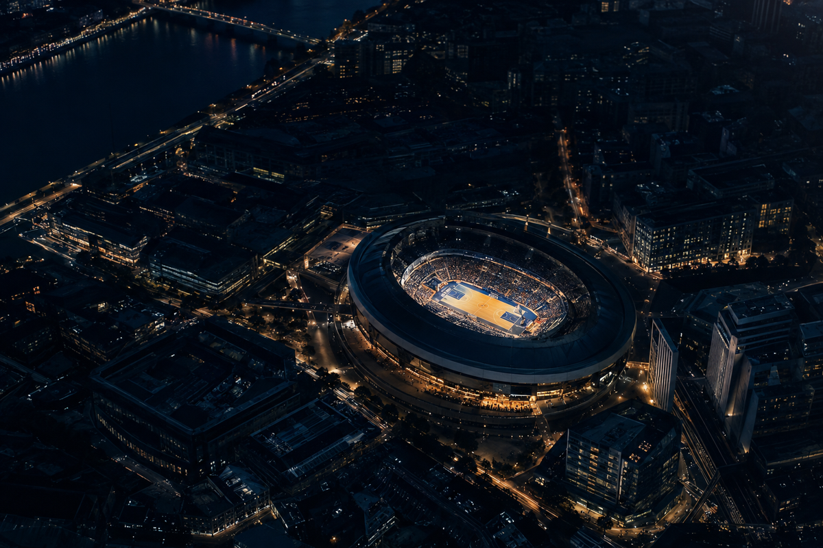 A lit basketball arena at night surrounded by a European city