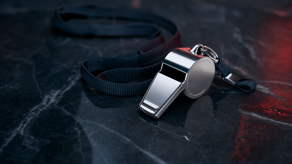 A chrome referees whistle on a dark lanyard against polished black stone with a red accent glow — illustration for a research note on Sportradar's counterparty risk.