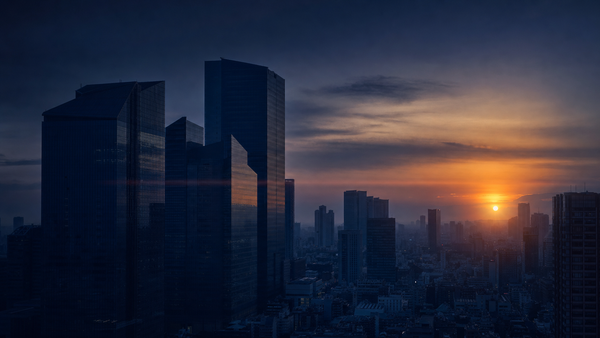 Editorial photograph of an abstract Tokyo financial-district skyline at dusk, dark indigo sky with a warm amber sun on the horizon, symbolizing Japan's shifting rates and currency regime.
