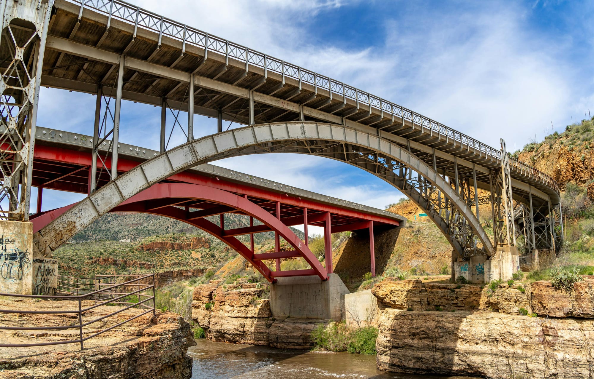 Dual bridges spanning the scenic Salt River Canyon in Arizona with striated rock faces and desert grasses.