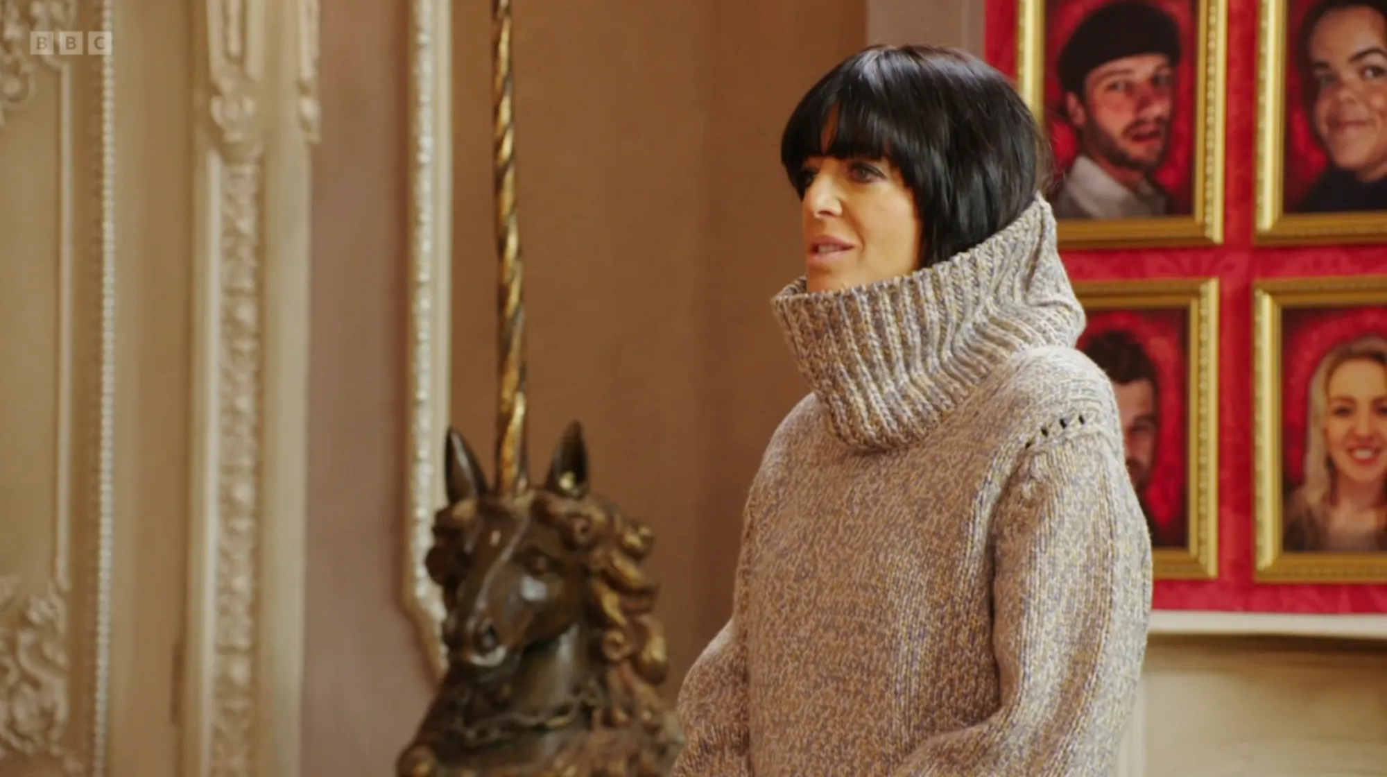 Host Claudia Winkleman in a still from The Traitors in which she's wearing a hilariously oversized turtleneck sweater that's practically covering her whole head